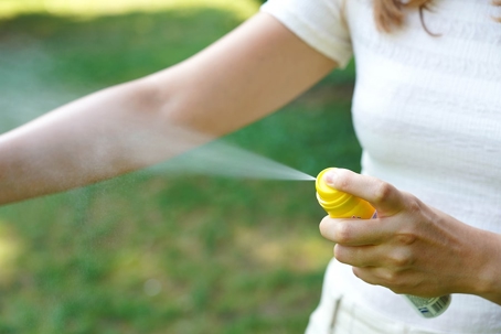 A woman is using a insect repellent spray