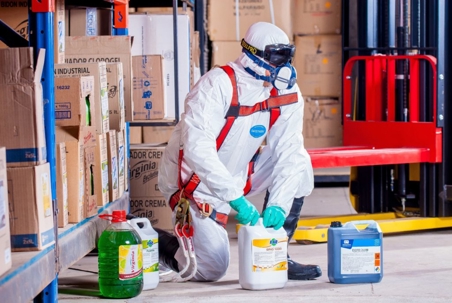 Man wearing full hazmat using some cleaning materials/liquids
