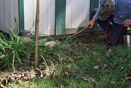 A man in a camouflage cap and striped shirt kneels on a grassy lawn