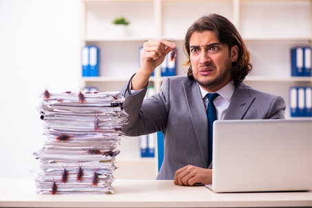 A disgusted businessman in a suit sits at his office desk